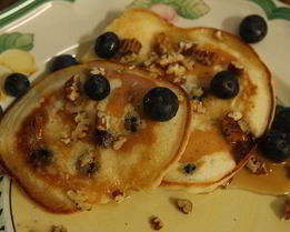 Банановые оладьи с кленовым сиропом, голубикой и орехами пекан