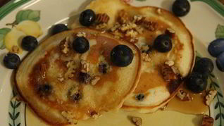 Банановые оладьи с кленовым сиропом, голубикой и орехами пекан